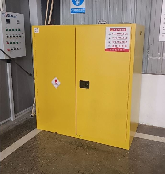 Yellow double-door flammable storage cabinet with CE mark and flammable warning labels installed in a plant room