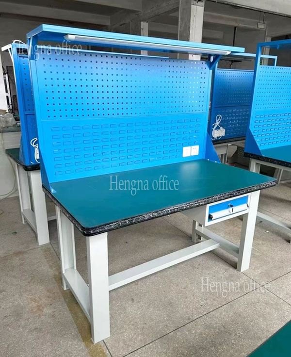 Heavy-duty steel workbench with pegboard back panel and drawer unit in a workshop