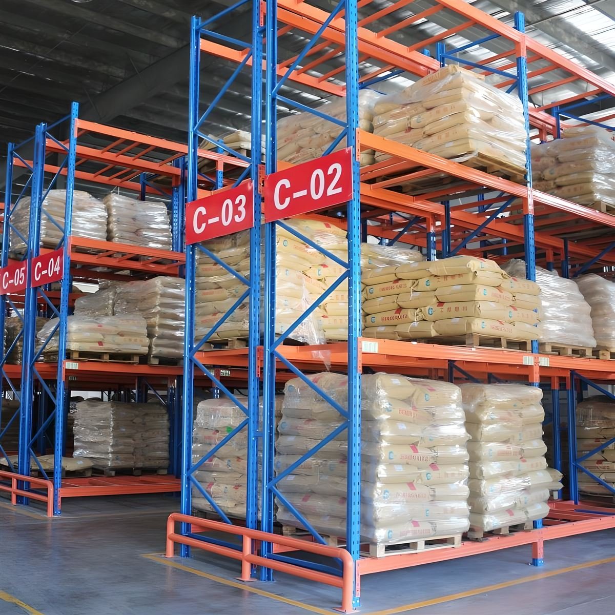 Heavy-duty storage rack with blue frames and orange beams loaded with pallets in a warehouse